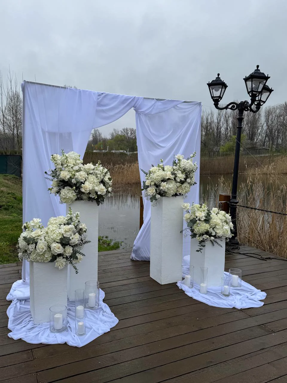 White wedding ceremony arch by the lake